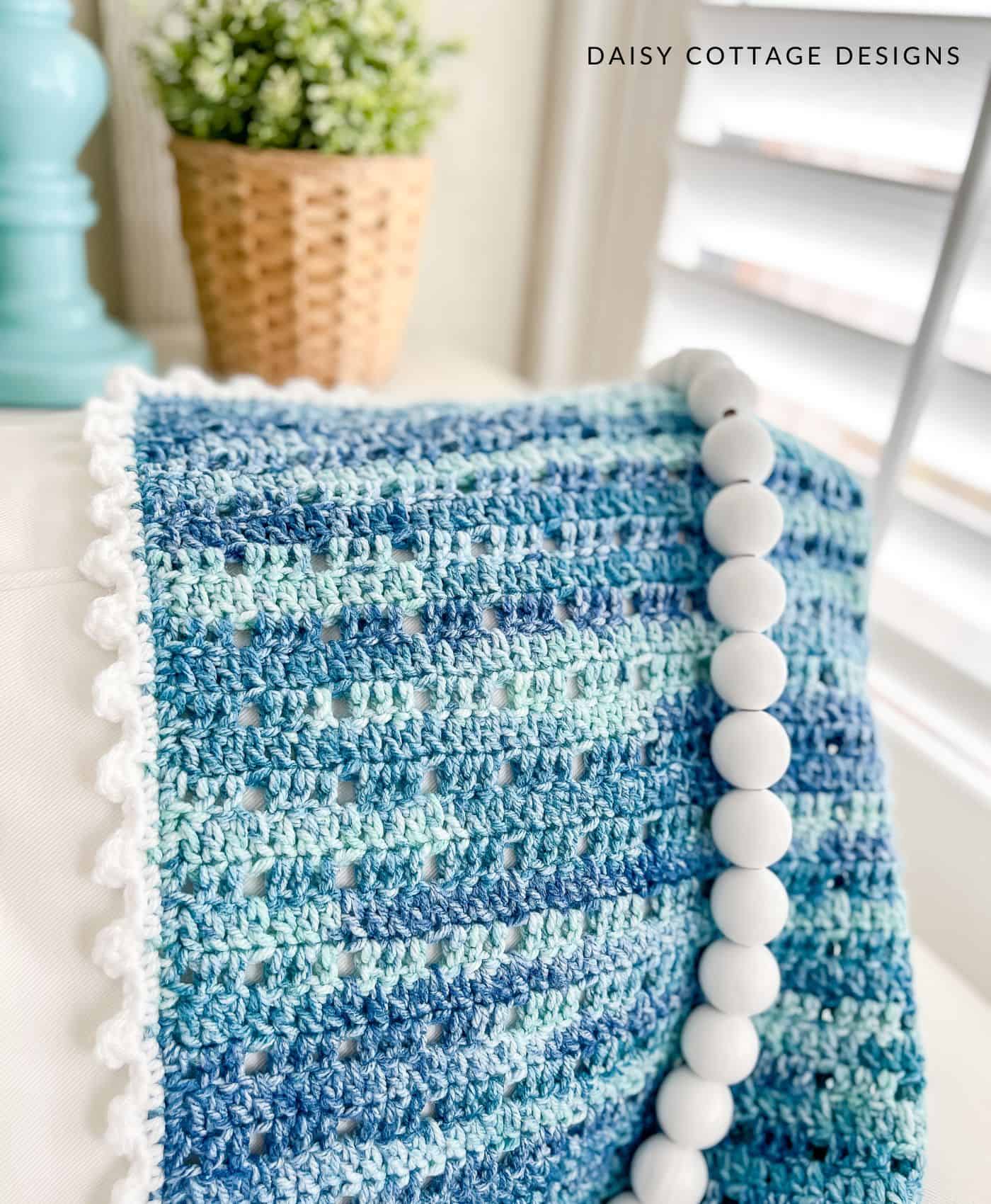 Blue crochet blanket with white picot border on a white couch