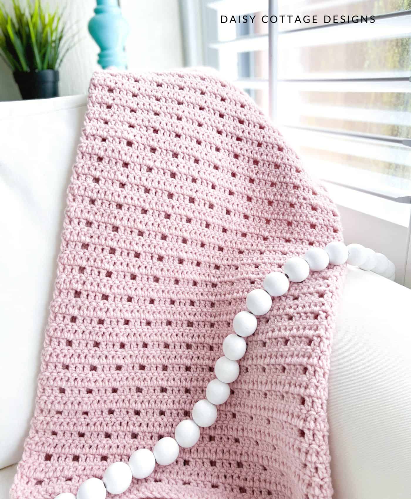 pink crochet blanket on white couch