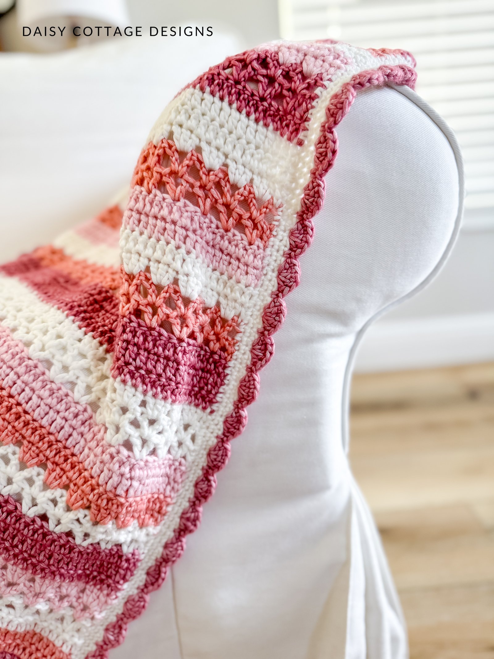 Close up of crochet blanket with a dark pink shell stitch border